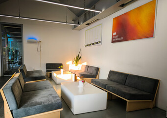 A contemporary waiting room with sleek design elements, featuring a comfortable seating area, modern art, and soft, natural light, creating a welcoming and relaxing atmosphere.