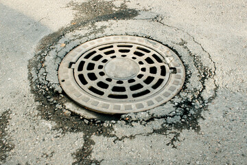 Sunken manhole cover in cracked asphalt — symbol of urban infrastructure failure, road repair and municipal services. Perfect for city planning, ecology and design projects.