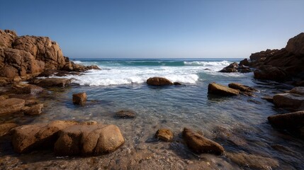 Rocky coastline with breaking waves and clear tide pools under a bright blue sky