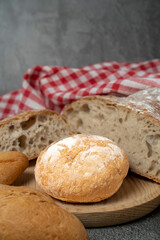 Assorted fresh bread, rolls, and a red checkered napkin resting on a kitchen counter