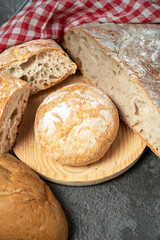 Assorted fresh bread and dinner rolls arranged on a dark table with a checkered cloth