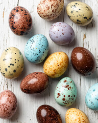 A close up shot of speckled easter eggs in various colors on a white wooden surface background view