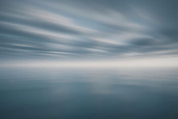 Fototapeta premium A tranquil seascape featuring gentle ocean waves, softly lit by a serene light. The calming tones of the water and light reflect a peaceful, almost meditative atmosphere, making it ideal for wellness.
