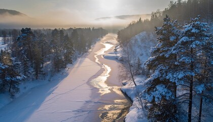 Captivating winter aerial view of a frozen river winding through a snow-covered forest with sunlight breaking through the trees creating a peaceful and serene natural landscape scene