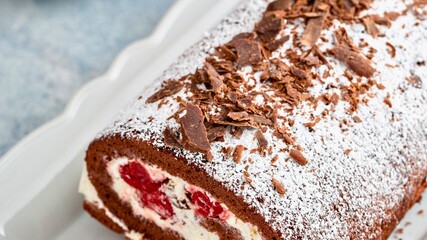 Decadent chocolate cherry swiss roll cake with whipped cream and chocolate shavings