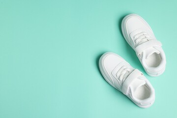 Pair of kid's sneakers on turquoise background, top view with space for text. Stylish shoes