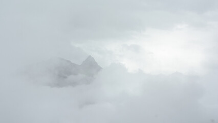 Alpine granite mountain peak covered in mist and clouds. La Vanoise national park, Savoie, France 