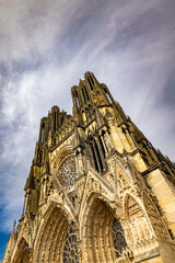 Reims, Marne, Grand-Est, France, August, 28th, 2025, Champagne Area, Stately cathedral front against dramatic sky scene, Vertical view of historic Gothic architecture with intricate