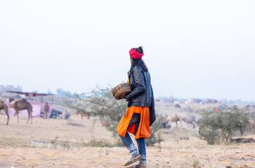 Portrait of  a young snake charmer male holding cobra snake with colorful turban at fair ground...