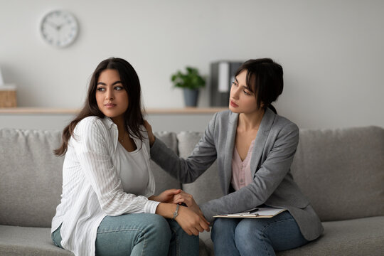 In a mental health clinic, a compassionate psychologist gently comforts an upset arab woman.