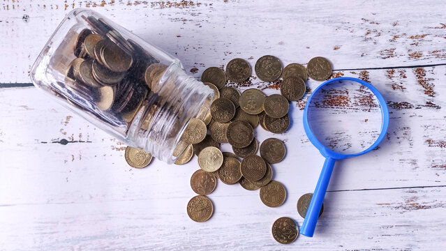 Financial Analysis: Magnifying Glass, Jar, and Spilled Coins for Money Examination
