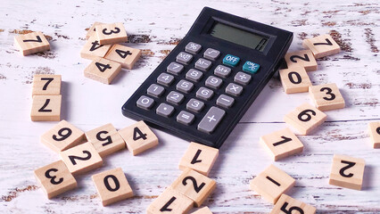Financial Calculation Chaos: Calculator Surrounded by Scattered Wooden Number Tiles