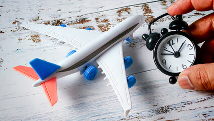 Managing Travel Time: Hand Holding Alarm Clock Next to Toy Airplane Model