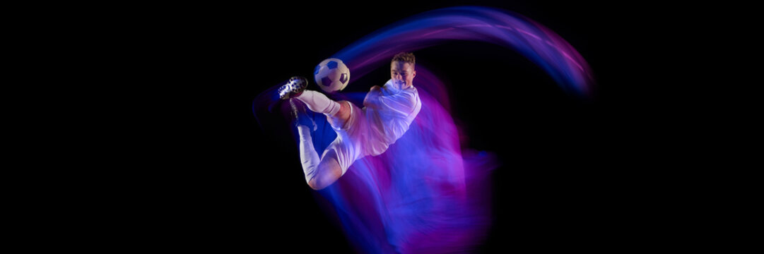Soccer player performing overhead kick with dynamic neon trail on black background. Concept of ambition, skill, courage, and drive in sport, fitness promotion, and creative advertising visuals. Banner