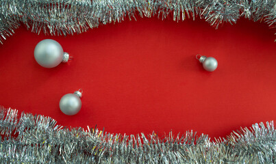 Christmas background with copy space. Christmas balls and tinsel on a red background.