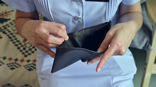 Cropped shot view of female nurse holding an empty wallet. Having financial problems means being unable to pay debts over the short or long term.