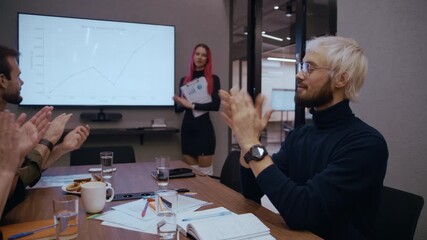 Colleagues sit around a meeting table in a contemporary office, applauding the presenter after her professional report on financial growth and investment trends - Powered by Adobe