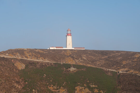 Lighthouse on hilltop under clear blue sky, coastal navigation landmark - Powered by Adobe