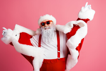 Santa in red suit with pink background dancing and posing for a festive photo wearing fur trim and...