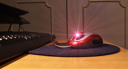 Ratón mouse con brillo y destello de luz roja, alfombrilla y teclado de ordenador