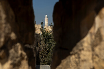 jerusalem, Israel, 2 November 2025, The white minaret of a religious structurey the tower of david, framed dramatically between two blurred, rough ancient stone walls,