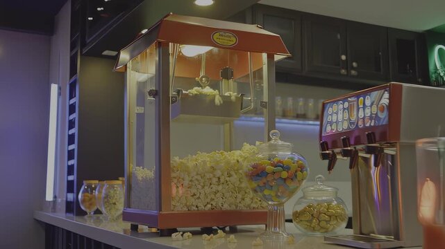 A movie theater concession stand with popcorn, candy, a soda dispenser, and drinks