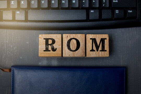 Wooden blocks with the letters ROM placed on a black computer keyboard, symbolizing computer memory, data storage, and technology concepts in modern digital systems.
