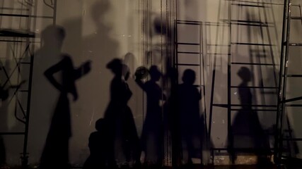Footage of shadows of dancers and stage crew projected on a backstage wall under dramatic
lighting creating artistic silhouettes and geometric ladder patterns in theater performance settings.