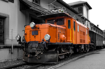 Historic electric locomotive in Bravuogn (Grisons Switzerland) now is tourist attraction near the famous alpine crossing railway. Colorful old maschine isolated on black and white grayscale background