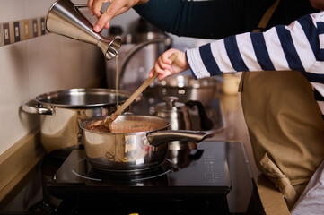 Family Kitchen Cooking: Pouring Broth Into Pot While Stirring With Wooden Spoon