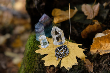 pentacle amulet, quartz crystals, fallen leaves close up on tree stump, autumn forest natural background. minerals for Magic crystal Ritual. Witchcraft, spiritual esoteric ceremony. Lithotherapy.