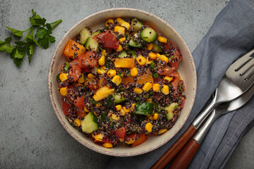 Quinoa salad with black quinoa, fresh tomatoes, corn, and cucumber representing healthy vegan and vegetarian food dark background