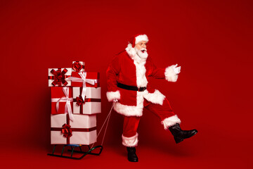 Santa in a bright red outfit pulls a sleigh of gifts beside a stack of wrapped presents for a Christmas promotion and holiday celebration scene