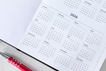 2026 new calendar year in notebook planner with pen. Annual goals, business budget, aspirations, monthly schedule concept. Top view.