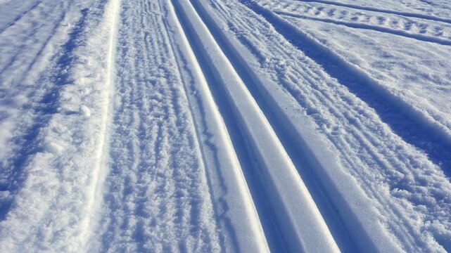 Prepared cross country ski track and snowmobile traces running through a vast snowy landscape toward a distant