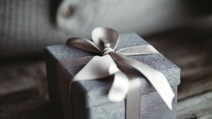 Hands carefully tying a ribbon on a gift box, preparing a present for someone special - Powered by Adobe
