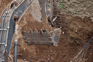 Excavator bucket digging into soil during construction work, showing power, precision, and heavy machinery in action.