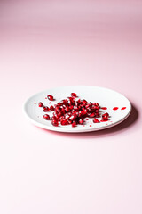 Close up studio shot of a pomegranate fruit showing seeds on a white palet