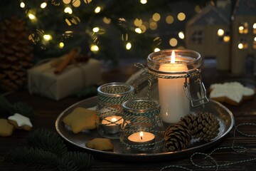 Christmas lanterns, cookies and festive decor on wooden table against background with blurred lights, closeup. Bokeh effect