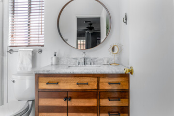 White modern bathroom interior with marble sink, wood cabinet, round mirror
