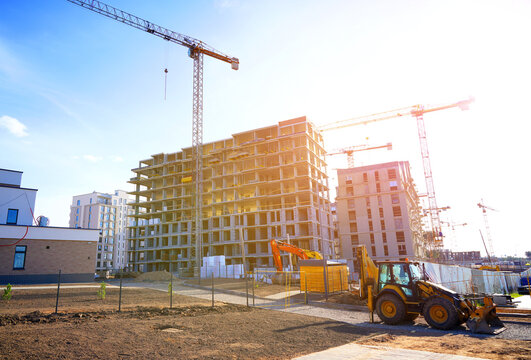 Construction site in modern urban area with cranes and machinery working. Heavy machinery working to erect new buildings. Tower crane on apartment construction. Block House building construction.