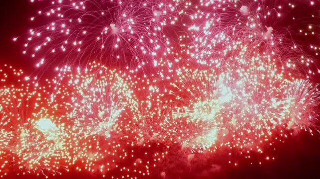 Brilliant bursts of red fireworks create an enchanting display, lighting up the dark sky with shimmering sparks and vibrant patterns, captivating all who gaze upwards in wonder.