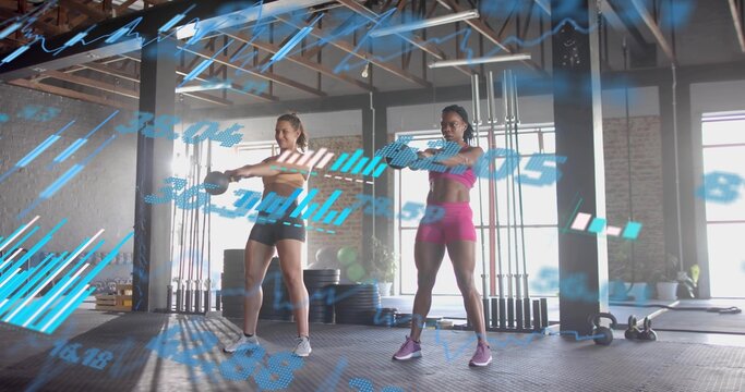 Performing front raises, women with kettlebells at gym, blue data overlay, in sports bras, shorts