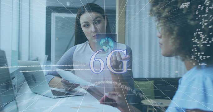 Reviewing woman in light top sharing documents and talking with coworker in office, laptop 6G label