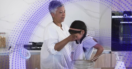 Wiping mature man white-shirt guiding child in apron at kitchen, mixing bowl, whisk, purple overlay