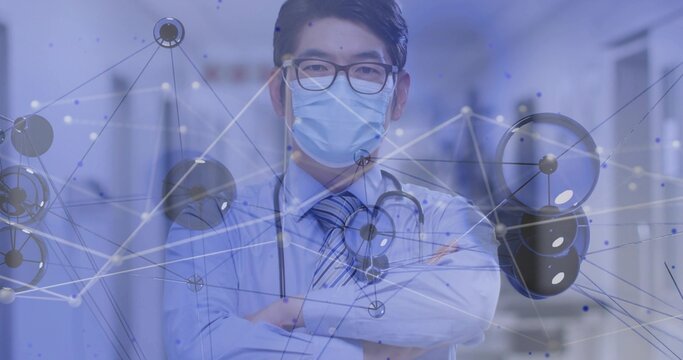 Standing doctor arms-crossed in hospital, wearing striped-tie, stethoscope, mask with data overlay - Powered by Adobe