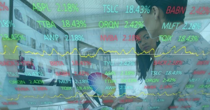 Viewing two in blazers leaning on laptop at office monitor showing colorwheel tickers, copy space