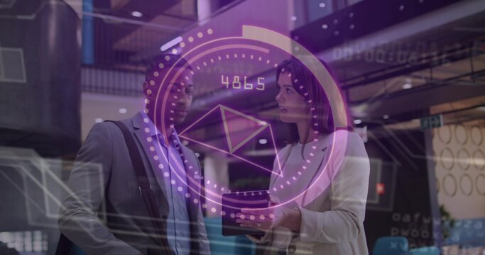 Discussing two colleagues in suit and blazer using tablet and viewing AR HUD in office atrium