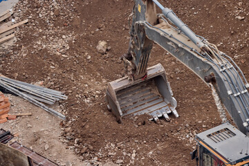 Excavator bucket digging into soil during construction work, showing power, precision, and heavy...
