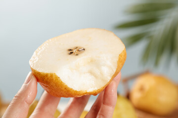 Hand holding cut Chinese pear showing soft white flesh and seeds